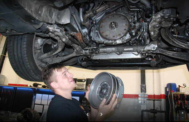 Mechaniker mit Kupplung unter Fahrzeug
