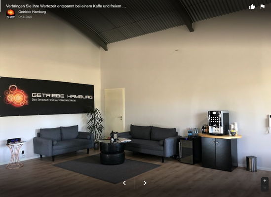 Wartebereich mit Couch und Logo an der Wand